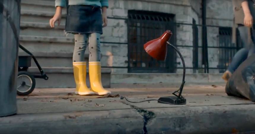 Girl in Rain boots stands next to red lamp